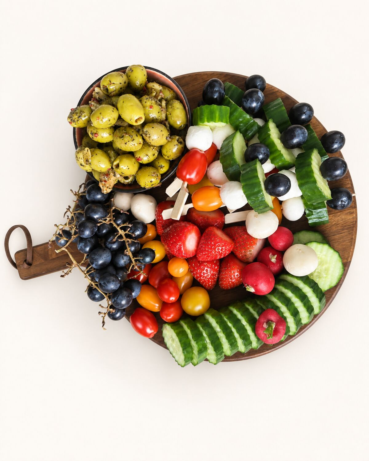 Ronde borrelplank met fruit, groente, mozzarella en olijven.